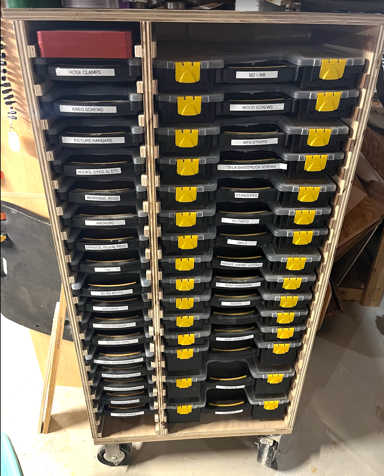 A wooden cabinent holding small and large Harbor Freight storage organizers